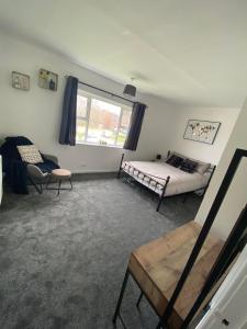 a bedroom with a bed and a couch and a window at Spacious & modern 3 bed house in Stafford