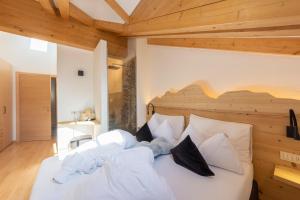 Schlafzimmer mit einem großen weißen Bett und Holzdecken in der Unterkunft Attico Faloria Luxury in Moena