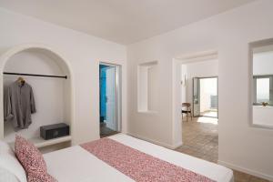 a white bedroom with a bed and a hallway at Asha Luxury Suites in Fira