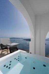 una casa con bañera de hidromasaje y vistas al océano. en Asha Luxury Suites en Fira