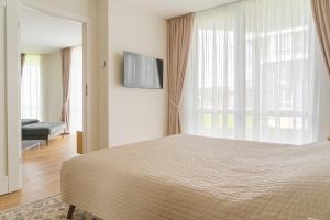 a bedroom with a bed and a large window at SimSim Apartamentai in Šventoji