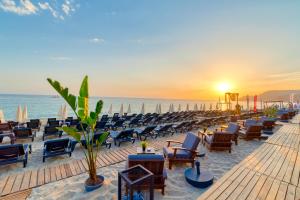 una playa con sillas y el océano al atardecer en Royalisa Palmiye Beach Hotel Adult Only, en Alanya