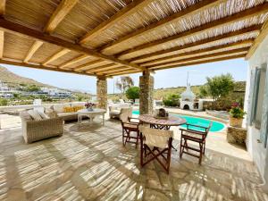 a patio with a wooden pergola and a table and chairs at Kalafatis Private Villa Mykonos in Kalafatis