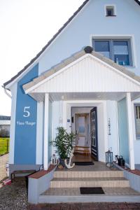 ein blau-weißes Haus mit einer Veranda und einer Treppe in der Unterkunft Haus Haeger in Dahme