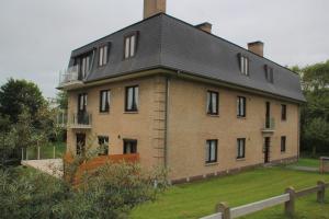 une grande maison en briques avec un toit en gambrel dans l'établissement Apartment Cuypers, à Oostduinkerke