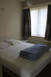 - un lit avec une couverture bleue devant une fenêtre dans l'établissement Apartment Cuypers, à Oostduinkerke