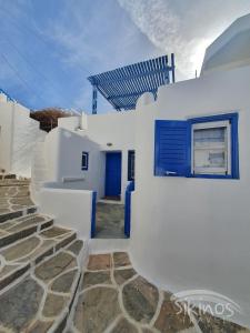 a white house with a blue door and stairs at Sikinos Summer Nest in Sikinos
