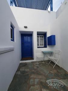 een kamer met een blauwe deur en een tafel en stoelen bij Sikinos Summer Nest in Síkinos
