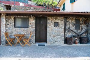 kamienny dom z drewnianymi drzwiami i dwoma krzesłami w obiekcie Antica Macina - “La Taverna” w mieście Rocchetta Nervina