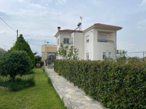 a white house with a hedge in front of it at Seaside apartment with private garden in Nea Anchialos