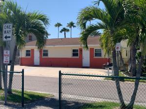 a fence in front of a building with palm trees at Michaels -Beachside Bungalows in St. Pete Beach