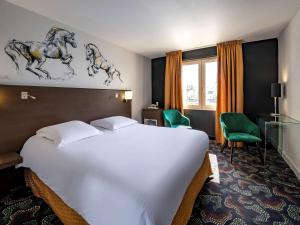 Habitación de hotel con cama blanca grande y escritorio. en Mercure Bords de Loire Saumur, en Saumur