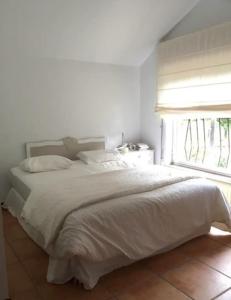 ein weißes Bett in einem Schlafzimmer mit einem Fenster in der Unterkunft Casa de los Belgas in Frama