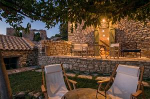 a patio with chairs and a table and a stone wall at Kyparissia Old Town Lodge with amazing sea view in Kyparissia