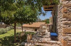 una casa de piedra con un patio con sillas y un árbol en Kyparissia Old Town Lodge with amazing sea view en Kyparissia