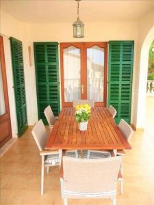 a wooden table with chairs and a vase of flowers at *****Villa de Món max. 8 Personen, Meerblick + Pool in Cala Anguila