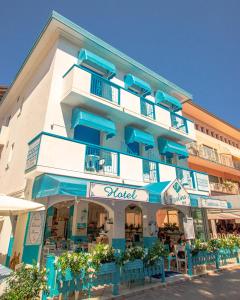 a large building with blue balconies and tables in front of it at Hotel Paolina in Lido di Jesolo