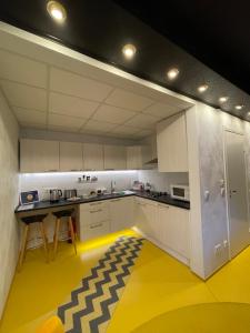 a kitchen with white cabinets and a yellow floor at Guest House Bermuuda Apartment in Paide