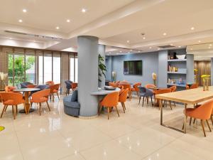 a restaurant with tables and chairs in a building at Phidias Piraeus Hotel in Piraeus