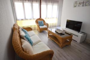 a living room with a wicker couch and a television at Golive Pepita in Cambrils