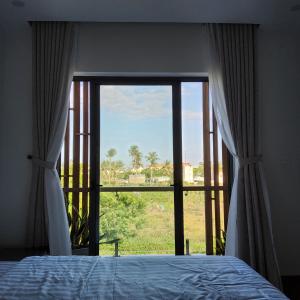a bedroom with a bed and a large window at Lacovy Home Hội An in Hoi An