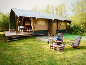 uma tenda com duas cadeiras em frente a um quintal em Glamped - Luxe camping em Westkapelle