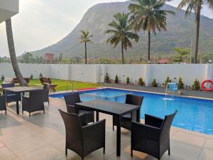 un patio con mesas y sillas junto a una piscina en SILVER CLOUD, en Nandigunda