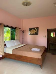 a bedroom with a large bed with a window at โพธิ์ทองริมทุ่ง Pothong Rimtung Hotel in Fang