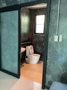 a bathroom with a toilet and a glass door at Baan Tonjaeng Resort in Chai Nat