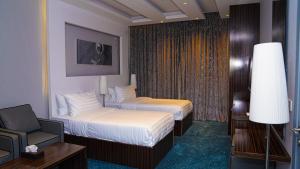 a hotel room with two beds and a chair at Clowzer Hotel- فندق كلاوزر in Riyadh +51 photos