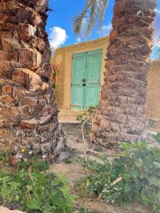 a house with a blue door and a stone wall at Sleep In Siwa in Siwa