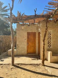 a house with a wooden door and a palm tree at Sleep In Siwa in Siwa