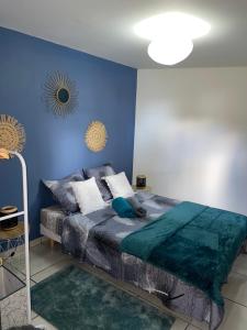 a bedroom with a bed with a blue wall at Le Coin Trankil in Saint-Louis