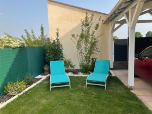 deux chaises bleues assises dans l'herbe dans une cour dans l'établissement Chez Jojo & Cassi, à Vert-Saint-Denis