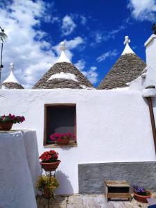 biały budynek z kwiatami w oknie w obiekcie Trulli Demetra w mieście Martina Franca +26 zdjęć