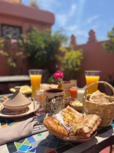 een tafel met eten en brood en glazen sinaasappelsap bij Riad Malfa in Marrakesh