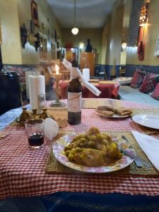 einen Tisch mit einem Teller Essen und einer Flasche Wein in der Unterkunft Kasbah Citoyenne in Agoudal
