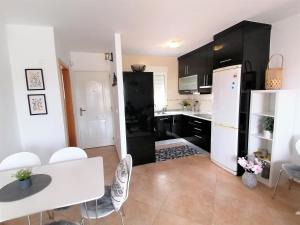 una cocina con armarios negros y una mesa y sillas blancas. en AL06- Modern 3 bed Duplex, close to beach in El Alamillo, en Puerto de Mazarrón