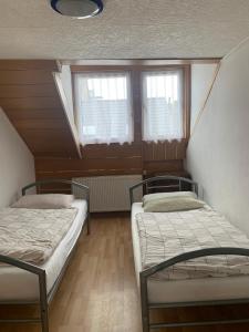two beds in a room with two windows at Dachgeschoss Hof in Krefeld