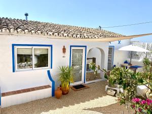 una casa blanca con una puerta azul y algunas plantas en Casa da Aldeia en Santa Bárbara de Nexe