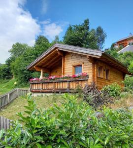 a log cabin with a balcony with flowers on it at Das Paradieschen in Edlitz