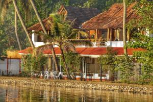 a house by the water with chairs and trees at Vala House in Cherai Beach