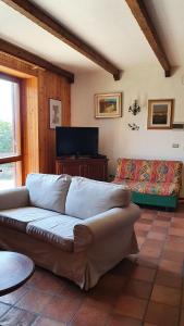 een woonkamer met een bank en een tv bij Dimora San Vincenzo in Pescocostanzo
