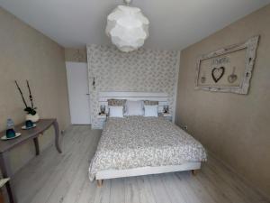 een slaapkamer met een bed en een kroonluchter bij Chambres d'Hotes des Ecureuils in Lanton