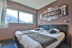 two beds in a room with two windows at Hôtel Les Flots Bleus in Savines