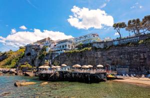a pier with umbrellas in the water near a beach at Hotel La Madonnina in Ischia