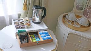 a table with a tray of books and a tea kettle at Fleurie Guest House in Torquay