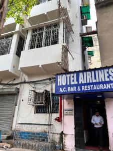 una entrada de hotel con un hombre de pie en la puerta en Hotel Airlines, en Calcuta
