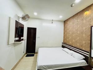 コルカタにあるHotel Airlinesの白いベッドと茶色の壁が備わるベッドルーム1室が備わります。