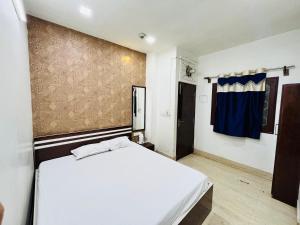 a bedroom with a white bed and a blue curtain at Hotel Airlines in Kolkata